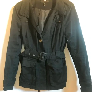 Svart Kort Trenchcoat/Jacka - Totally vintage. Väl använd men inga direkta defekter. Fodrad. Längd nacke/fåll 72cm.