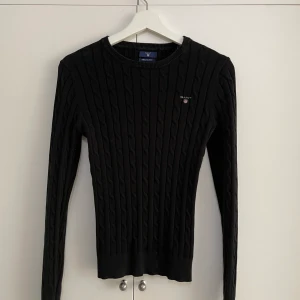 Äkta Gant kabelstickad tröja - Äkta svart Gant kabelstickad tröja köpt på Johnells. Storlek Xs, använd ett par gånger men i nyskick. Vid snabbaffär går priset att diskutera 