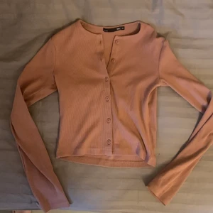 Rosabeige kofta - Säljer en rosabeige kofta som är helt oanvänd!  Koftan är ribbad och är i storlek S men skulle även passa XS.