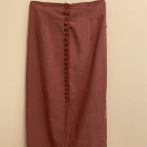 Rosa kjol - En rosa långkjol som har knappar i mitten  och funkar perfekt till fest. 