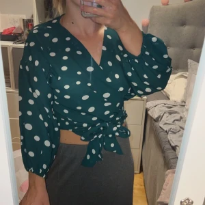 Grön Blus  - Jättefin grön blus i en bekvämt grönt material. Ballongaktiga armar, träskgrönt med vita prickar och knytning och lite kortare armar. Passar fest, utekväll och myskväll!  Kan postas eller mötas upp med ett avstånd av 30-40min hemifrån.