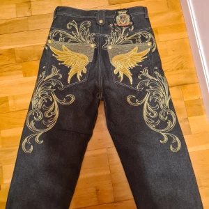 Y2K jeans - Skitfeta y2k jeans med guldigt broderi. Som knappt är använda för att de passade aldrig riktigt min stil. De är i väldigt gott skick. Fråga i DM för fler bilder :)