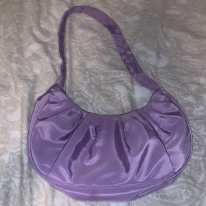 Nylonväska  - Jättesöt väska i lila färg, lätt att bära och livar upp ens outfit. Pris kan som alltid diskuteras, frakt ingår ej i priset köparen står för frakt själv! 