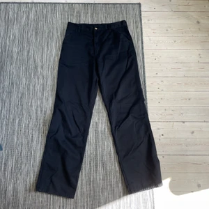 Carhartt Chinos - Ett par vintage Carhartt chinos, svart färg. Relativt bra skick, inga hål, permanenta fläckar eller liknande utan de har bara blivit väl använda utav mig. Säljes däremot för att de inte kommer till användning längre då jag vuxit ut de! De är lite små i storleken men passar ungefär 31/32 eller 32/32!
