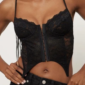 Korsett i spets - Ny korsett i spets från NAKD. Lappar kvar! Justerbara band, ovadderade kupor & knäppning fram. Strl 70C passar XS/S