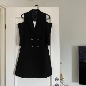 Kavajklänning - Snygg kavajklänning med öppna armar upptill (se bild). Aldrig använd, prislapp kvar! Nypris 899kr.