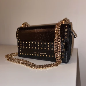 Väska svart - Väska från ideal of sweden. Använt få gånger. Justerbart kedje-band som gör att man kan ha den korsad över bröstet eller runt axeln.  Mycket fin och bra väska som passar till allt men behöver ett nytt hem. 