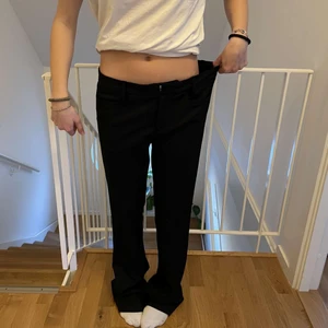 Lågmidjade svarta kostymbyxor  - Ett par svarta kostymbyxor med perfekt passform! De sitter lågmidjat och är straight leg/pyttelite vida i benen.