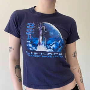 Kennedy space center babytee - Mörkblå vintage babytee med sött Kennedy space center print. Gjord av 100% bomull, väldigt mjuk och bekväm. Fint vintage skick med något slitet tryck, ett mindre hål i ena armhålan, lätt återgäldat om så önskas men syns inte när man har t shirten på sig. Armhåla till armhåla 42cm, längd från axel till nedre sömnad 50cm. Jag brukar ha Small/36 i toppar och är 171 cm lång. Kan mötas upp på södra sidan av stockholm annars står köparen för spårbar frakt 66kr. Skriv vid frågor 💌