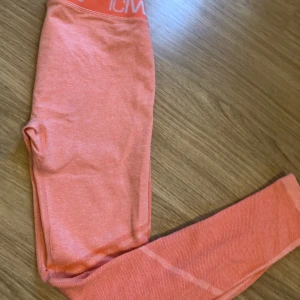 ICIW träningsbyxor - Ett par träningsbyxor från ICIW som är rosa/korall. Byxorna har ett hål vid sömmen (se bild) som en sykunnig säkert kan fixa. I övrigt så är ddm i vra skick