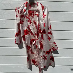 Jättefin silkesklänning i rosa/vitt med röda blommor på, från Gina. Endast använd en gång så är i fint skick!