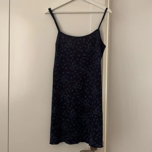 Vintage minidress, ungefär storlek M - Mörkblå miniklänning med små blommor på. Det står ingen storlek på, men skulle uppskatta att det är en storlek M. Det hänger små trådar från ena axelbandet, annars är den i bra skick 