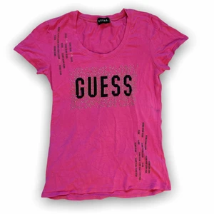 Guess t-shirt - Rosa Guess tröja med coolt svart + silvrigt tryck och rhinestones💕 Så söt verkligen!!  Den är lite urtvättad, och nån enstaka rhinestone har ramlat av men skulle inte säga att det syns alls. Passar XS-S 🌺