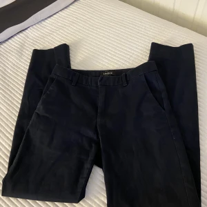 Mörkblåa kostymbyxor - Marinblåa kostymbyxor från Lindex. Något kortade modell. Modellen heter Iris. Stolek 34.