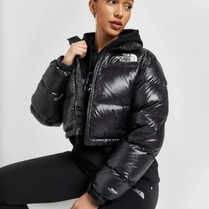 Croppad Northface jacka - Säljer denna supertrendiga svarta ”The north face” jacka. Den är croppad (kommer lite under midjan) och glansig.💕Storleken är M men om man vill ha den ganska ”fitted” passar den L också men om man vill ha den lite oversize kan den passa storlek S. Buda🫶🫶🫶