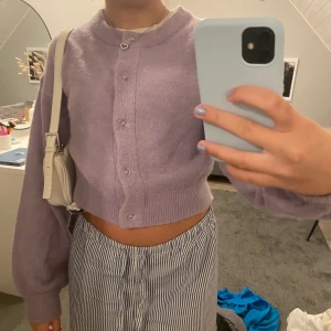 Lila stickad kofta - Säljer denna jätte mysiga lila stickade koftan, knappt använd. Från hm, man kan ha den bakifrån också så det blir en vanlig stickad tröja. Storlek xs Säljer även den vita väskan på bilden!