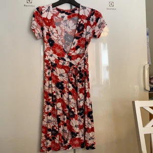 Lingon och blåbär  - Klänning från lingon och blåbär storlek M. Porto 60kr spårbart med post nord. Klänningen är i mycket gott skick. Förutom tråden har lossnat lite på själva omlott snörningen. Jättefin nu till sommaren🤩