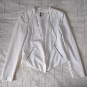 Kort vit kavaj/jacka, storlek 36 - Vit/off white kavaj/jacka i en lite kortare modell. 71% polyester 23% viskos 6% elastan, foder: 100% polyester. Använd en gång och så gott som ny. Storlek 36.