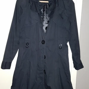 Svart tunn kappa - Jättesöt svart tunn vårkappa från Miss Baron strl 36. Har veckad kant i nacken och fina detaljer. Säljes för endast  150 kr. Mycket gott skick!