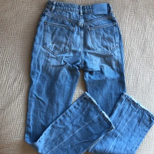 Jeans  - Säljer dessa fina hömidjade blå jeansen från BERSHKA. Hålet på det högra knäet har gått upp lite som man ser på tredjebilden och längst ner på bensömmen är de lite nedtrampade, men annars är de nästan så gott som nya. Lite osäker på storlek men tror 36