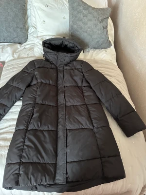 Lång svart dunjacka  - En lång svart dunjacka från H&M i storlek M. Inköpt vintern 2022 men använd fåtal gånger under den tiden.