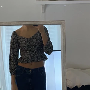 Svart topp - Somrig svartvit topp från bil bok med ett svart-vitt blomtryck. Aldrig använd, prislappen kvar. Storlek M men passar S också. Valfritt hur man bär den över axlarna