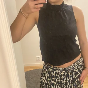 SVART TOPP - Svart topp med hög volangkrage. Så snygg med en perfekt längd till jeans eller andra byxor. Få gånger använd från Lindex, köpt för 349kr