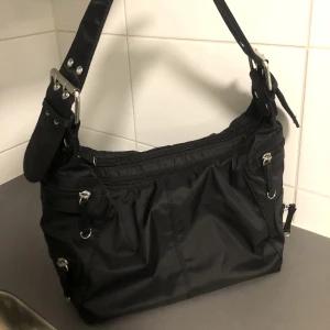Svart handväska  - En medelstor hand/axelväska i svart med snygga silvriga detaljer 💥 i fint skick. Frakt 60 kr 