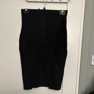 Svart pennkjol som kramar om kurvorna fint - Svart pennkjol från Bikbok strl S, sitter tajt och kramar om kurvorna fint. Går ner till knäna. Slits baktill.