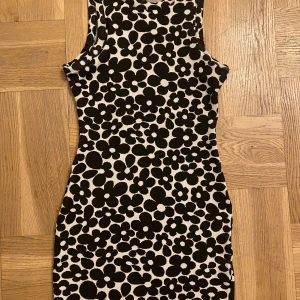 Figursydd klänning med blommigt mönster - Säljer denna figursydda klänning med svartvitt blommigt mönster från H&M, då den helt enkelt inte var min stil. Lappen sitter kvar! Betalningen sker via Swish. Står ej för postens slarv!