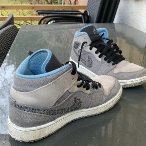 Air Jordan 1 Mid 'Crater Grey University Blue  - Storlek 42.5.  Skorna är använda under en kortare period och skicket är riktigt bra. 
