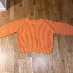 En stickad tröja i färgen orange.