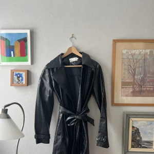 Lädertrench  - Svart lädertrenchcoat i fejkat ormskinn. Toppen skick! 