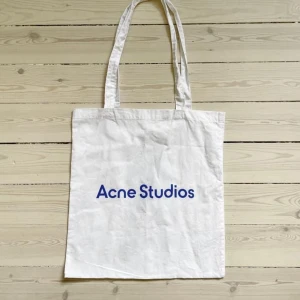 Acne Studios Tote bag - Acne Studios Tygväska/påse med fint tryck på baksidan. Har någon enstaka fläck som säkert går bort i tvätt (se bild) Annars knappt använd och som ny. 