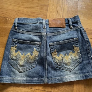 Kort jeanskjol - Kort jeanskjol med detalj på bakfickor. Från H&M (skulle gissa runt 2005-2010), köpt secondhand. Köpare står för frakt :)