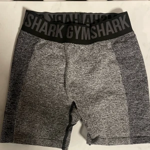 Korta gymshark tränings byxor  - Ett par korta gymsharks byxor som är grå och skiftar lite till mörkare, är i storlek S och i bra skick. Kontakta om frågor!!