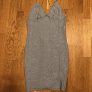 Glittrig klänning - Jättefin blåglittrig festklänning med en liten slits längst ner. Öppen rygg, figursydd, slutar ovanför knäna, väldigt bra skick!