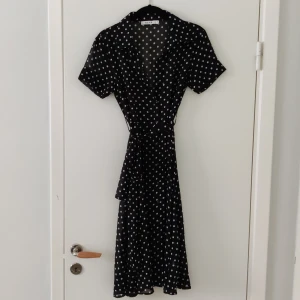 NA-KD klänning - En sval, tunn, see-through klänning med knappar hela vägen ner, band runt midjan och krage. Väldigt stilren och passar till många event😍