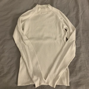 Vit stickad tröja - Vit stickad tröja som är lite högre i kragen men är inte polo. Väldigt skön och stretchig.