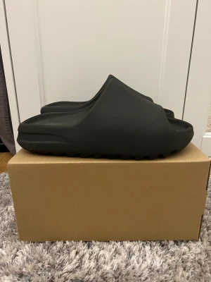 Yeezy slide onyx - Säljer mina yeezy Slides då dom har blivit för små. De är i skicket av ett par nya men har använts ett par gånger.