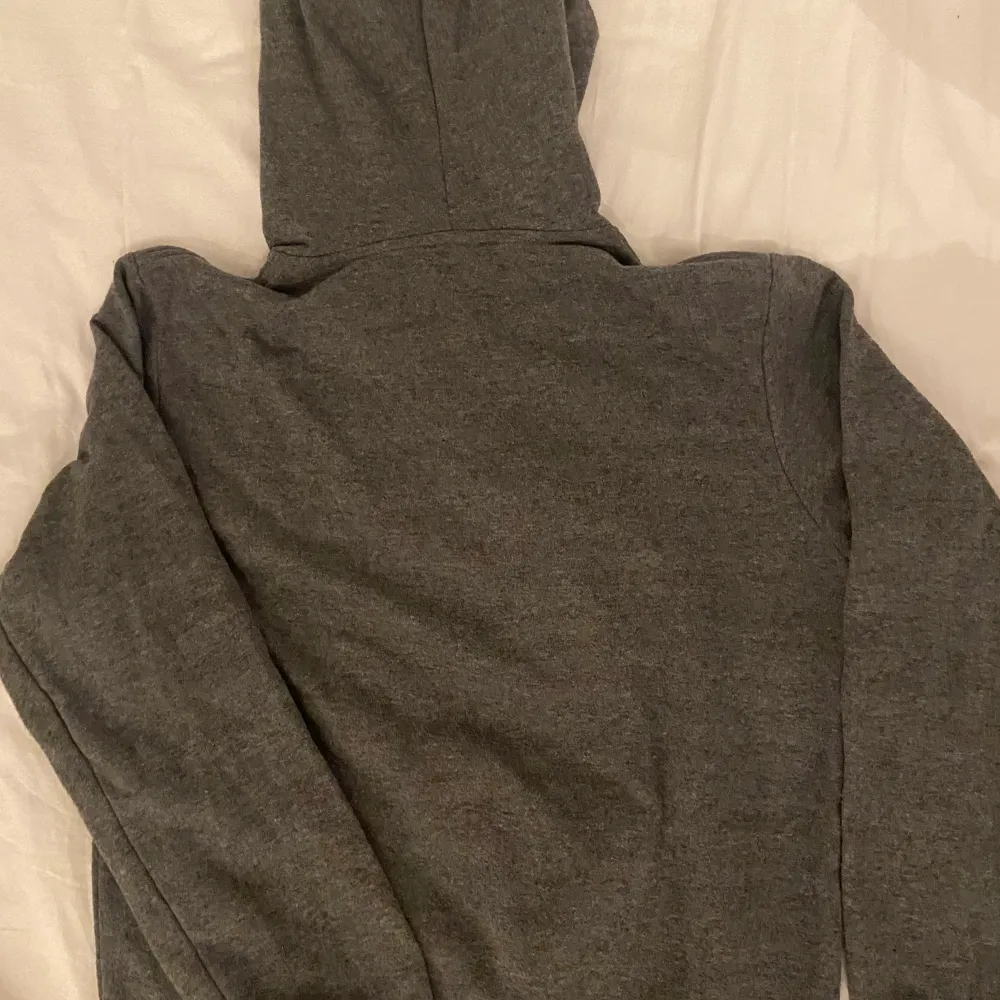 Säljer en mörkgrå Champion hoodie med coolt tryck på både framsidan och ärmen. . Hoodies.