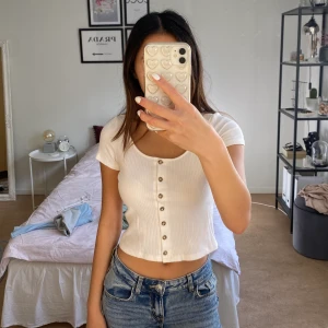 Monki t-shirt med knappar - Jättegullig ribbad tröja från Monki med knappar. Finns ett jättelitet hål (bild 2) men som knappt syns. Kan mötas upp eller frakta.