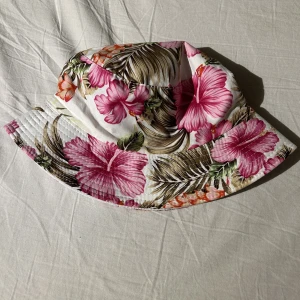 Buckethat  - Buckethat i antingen blommigt mönster eller helvit. 