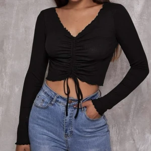 Topp m. dragsko - säljer denna korta toppen med dragsko mellan bysten.