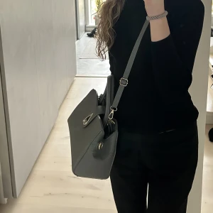 Väska  - Ljusgrå handväska, knappt använd. Köpt secondhand och   saknar ett spänne men går att avända den som vanligt. Köparen står för frakten💕