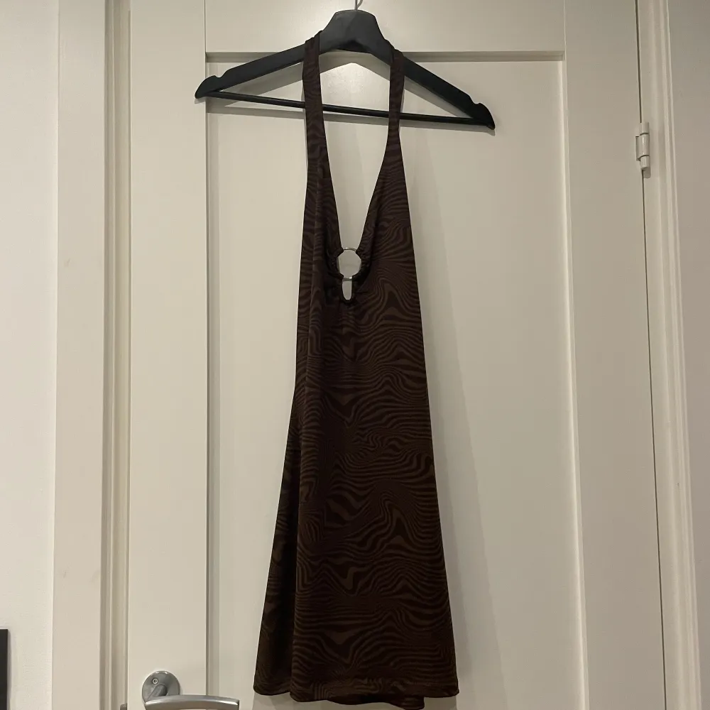 En mörkbrun klänning med nästan lite zebramönster och öppen rygg. Den kommer ursprungligen från H&M och jag har den i stl M. Har aldrig kommit till användning så den är i toppen skick! . Klänningar.