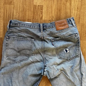 Levi’s Jeans - Mått: W34, L32) i okej skick förutom ett hål som sytts igen under skrevet, samt ett hål i fram och ett i bakfickan. Finns att hämta upp eller frakta via postnord