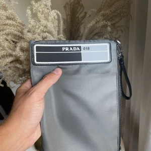 Prada 018 perfekt julklapp🎁 -  Lite information; Det är en större variant av en börs. En börs som är lika stor som en iPad. Korthållare finns såklart. Får plats med väldigt mycket så man slipper bära på en ryggsäck. Skicket är 10/10, alla tillbehör finns. Skriv för mer info eller 📸 