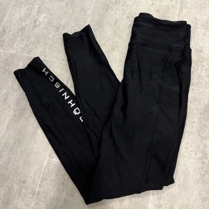 Röhnisch Shiny träningstights  - •Oanvända  •stretch •Svarta träningstights i en shiny yta.  •andningsbart tyg som leder bort fukt från huden •medelhög midja med brett midjeband •justerbar dragsko i midjan  •reflekterande röhnisch logotyper på baksidan smalbenet 