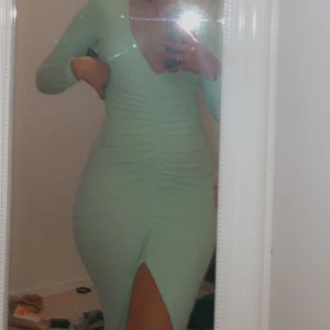 Mintgrön - Säljer min älskade mintgröna kläning som är figursydd, har drapering där fram och en jätte snygg slits. Använd endast när bilden togs.